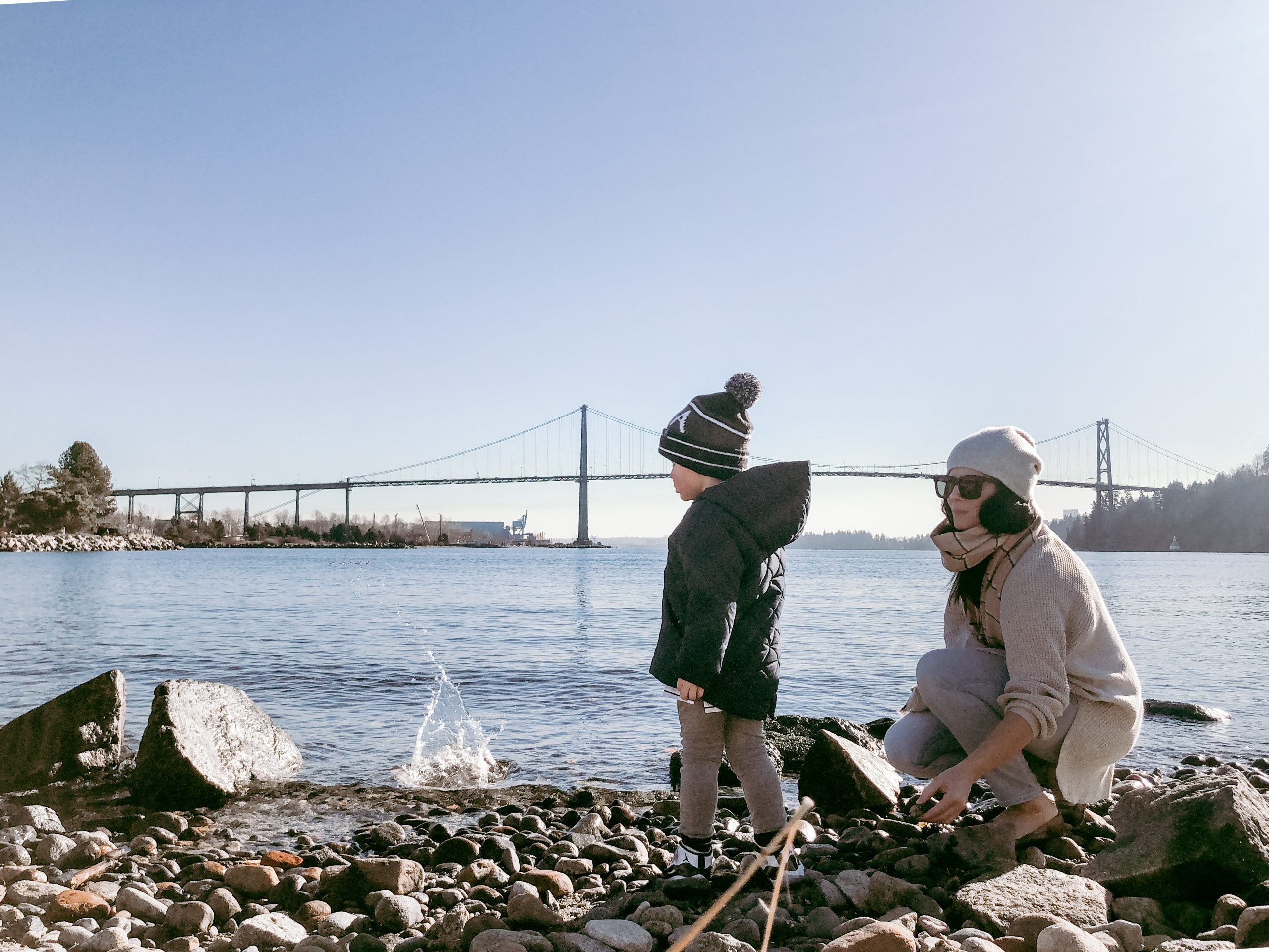 Woman and child on beach with bridge in background
